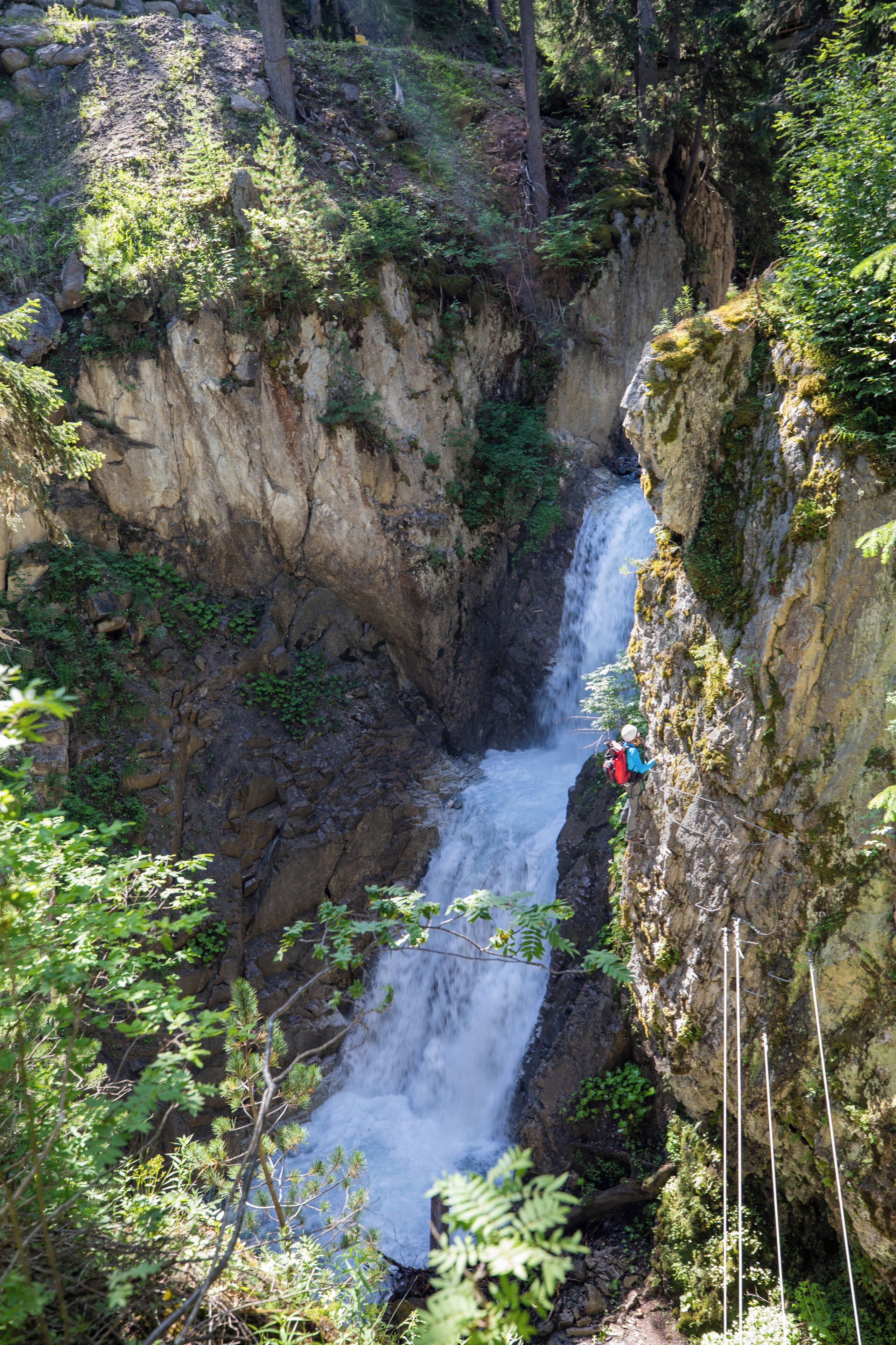 A waterfall in a rocky gorge with a person taking a photo.