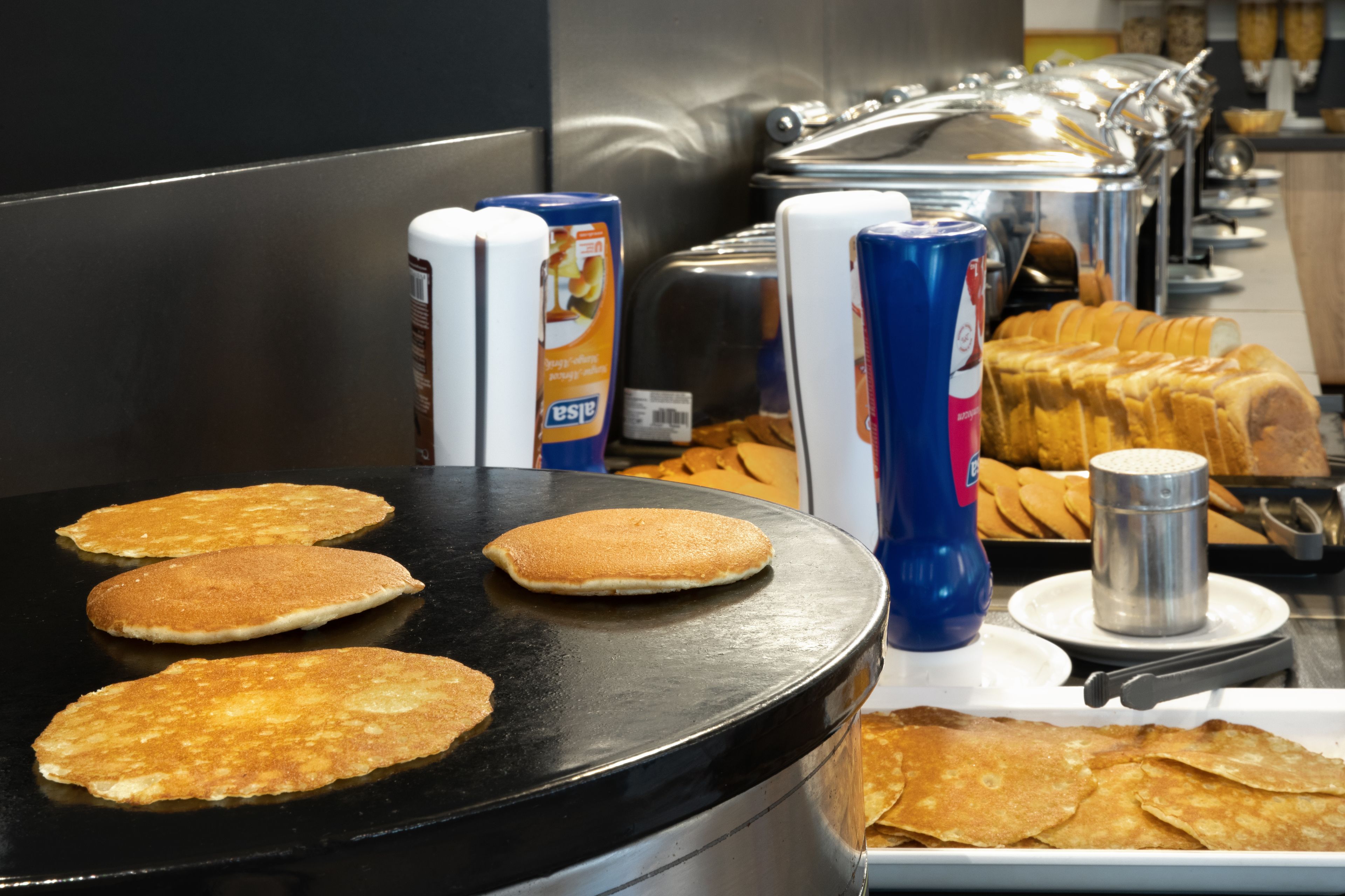 Un bufé de desayuno con panqueques, tostadas y bebidas.