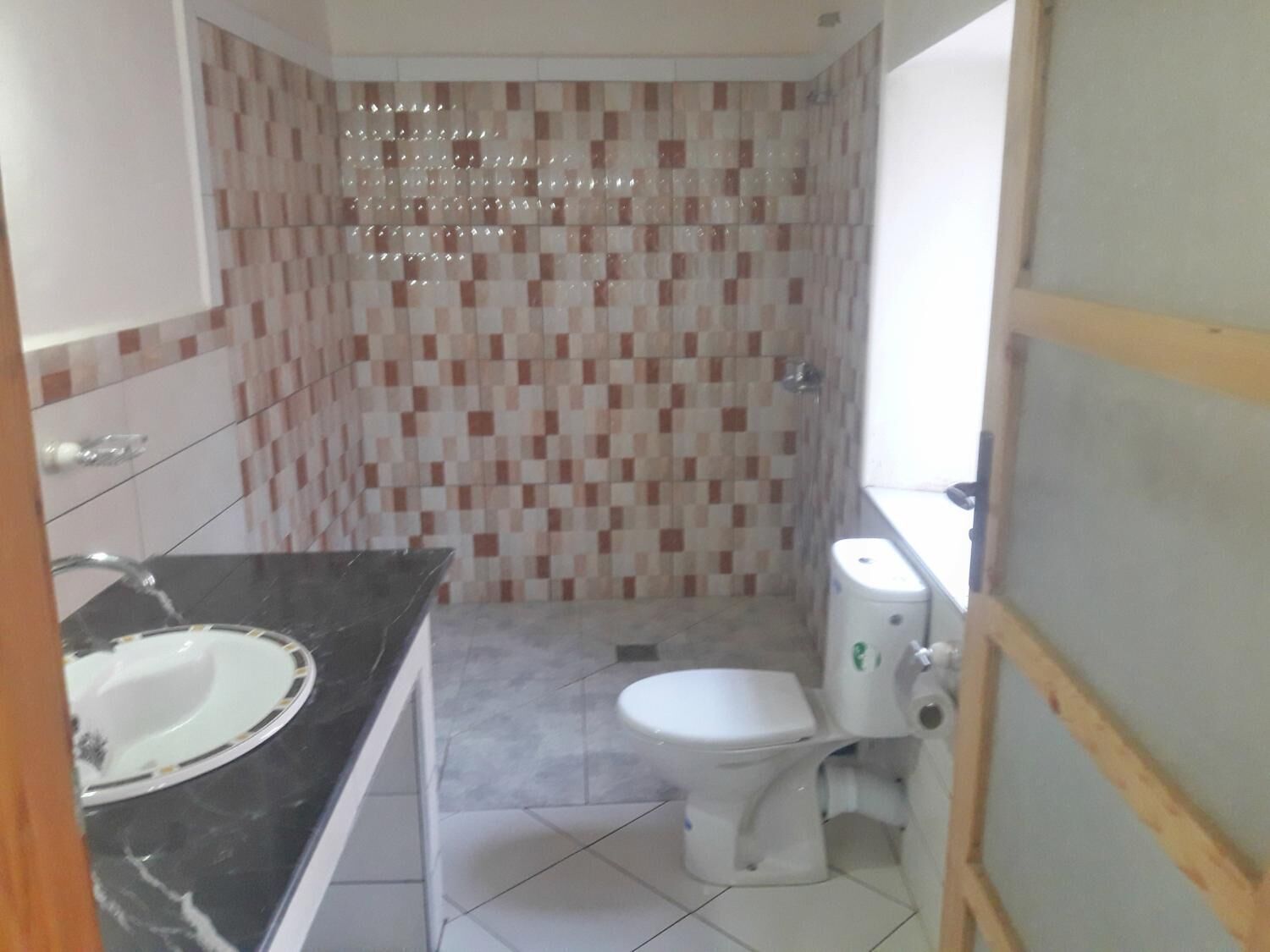 Un baño con ducha de azulejos, inodoro y lavabo.