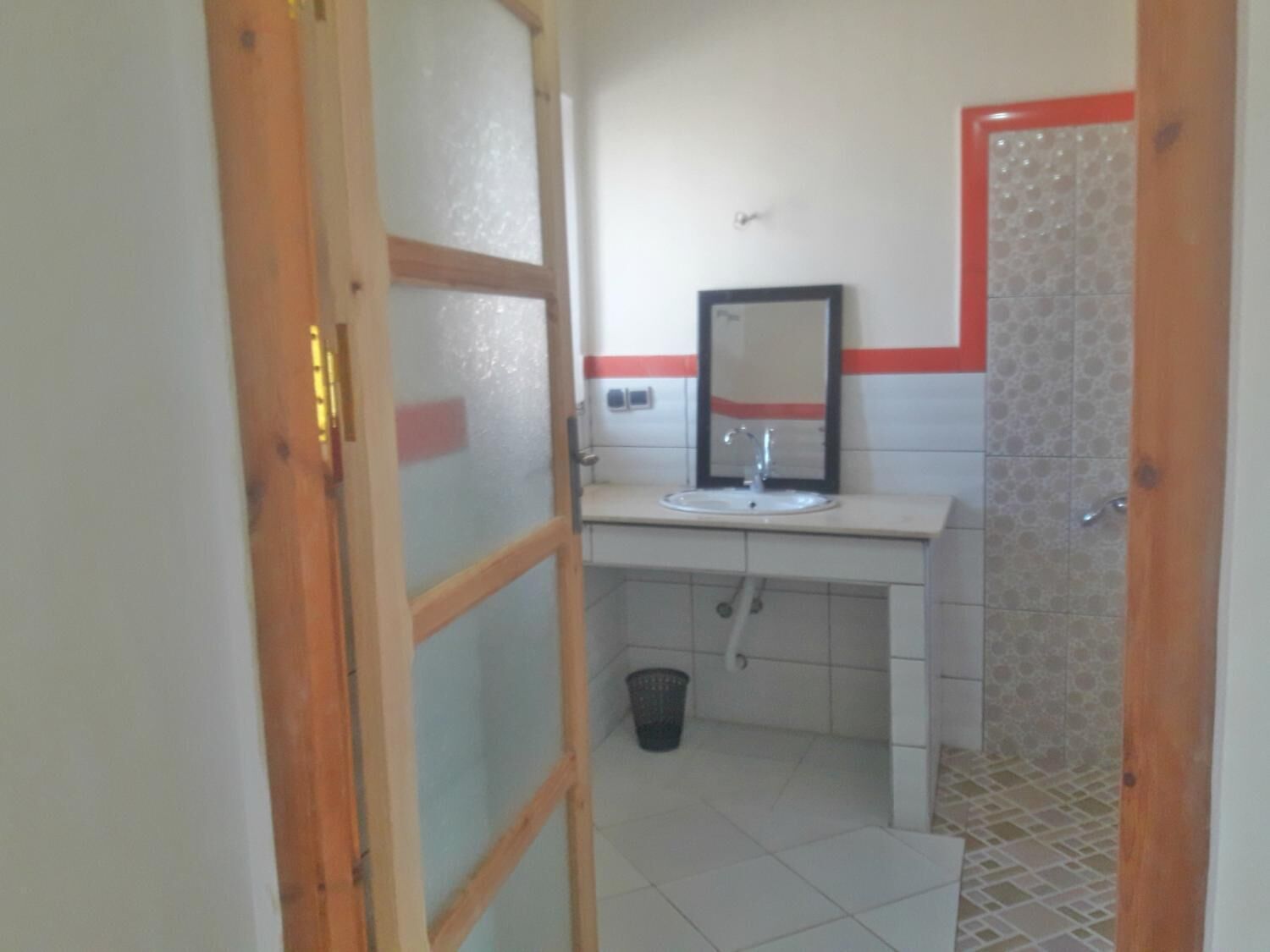 A bathroom with a white sink, mirror, and tiled walls.