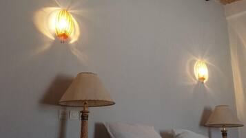 A room with two wall-mounted lamps and two table lamps on a bed.