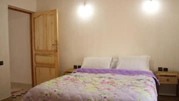 A bedroom with a bed, a wooden wardrobe, and two bedside tables.