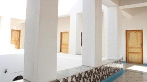 Un pasillo con paredes blancas y puertas de madera que da acceso a habitaciones individuales.