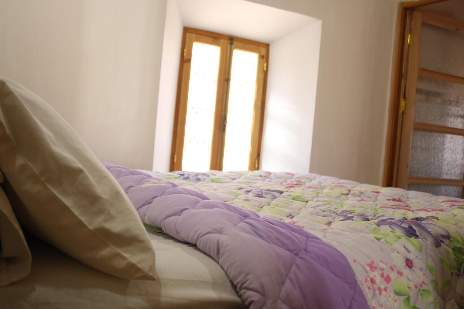 Um quarto com uma cama, janela e porta.