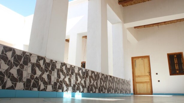Un interior espacioso con techos altos, una pared de azulejos y una puerta de madera.