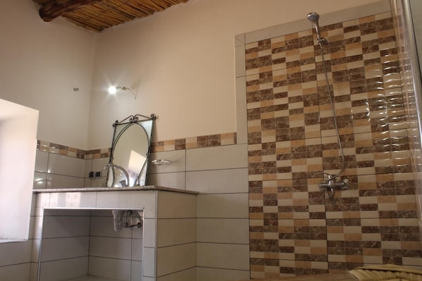 A bathroom with a shower, a mirror, and tiled walls.