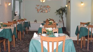 A dining area with tables set for service, chairs, and a decorative wall with a geometric pattern. - The Northdale Hotel Ltd (Skegness)