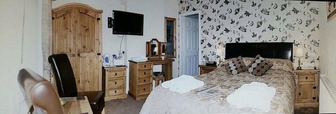Un dormitorio con cama, cómoda de madera, escritorio y televisor.