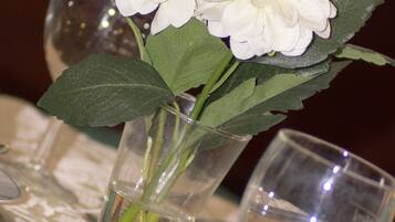 A table with a vase containing white flowers and two clear glasses.