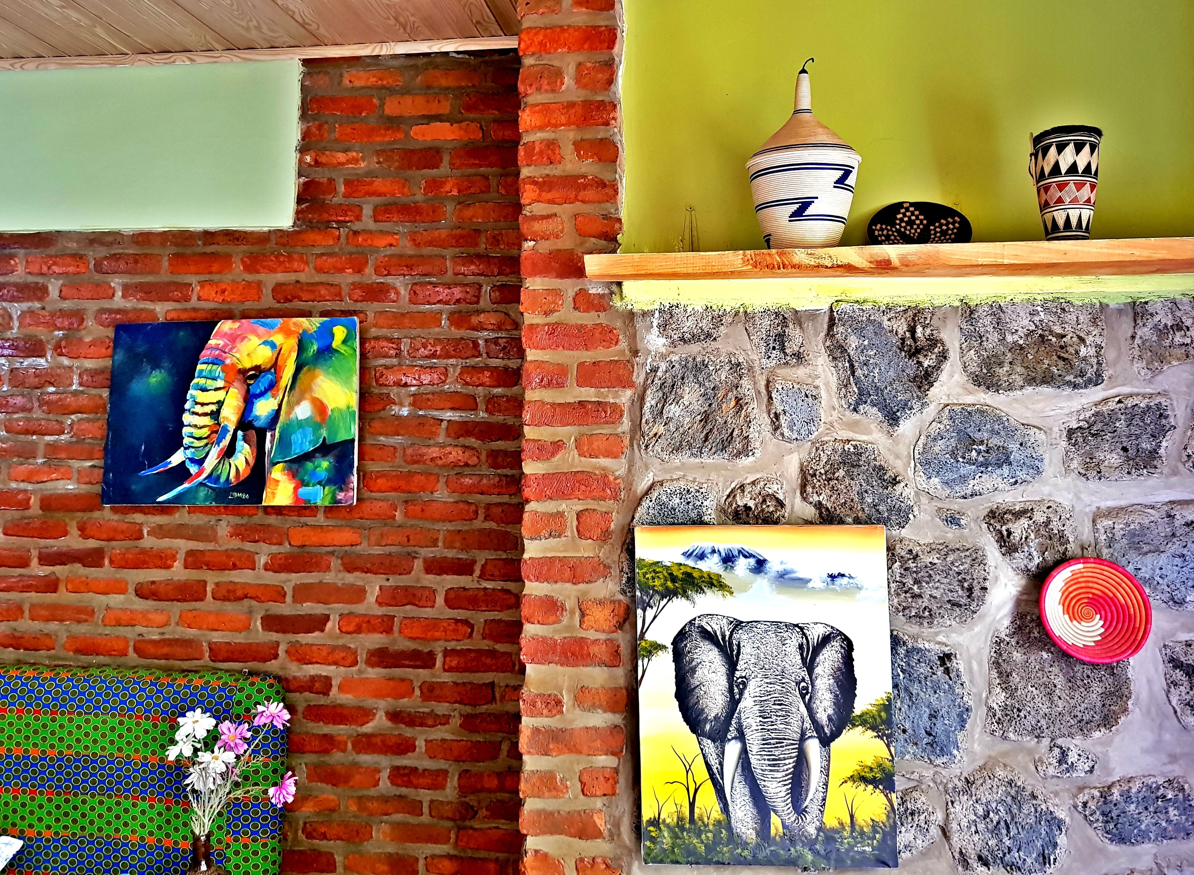 A room with a brick wall, a green wall, and a stone wall. There are paintings and decorative items on the walls.
