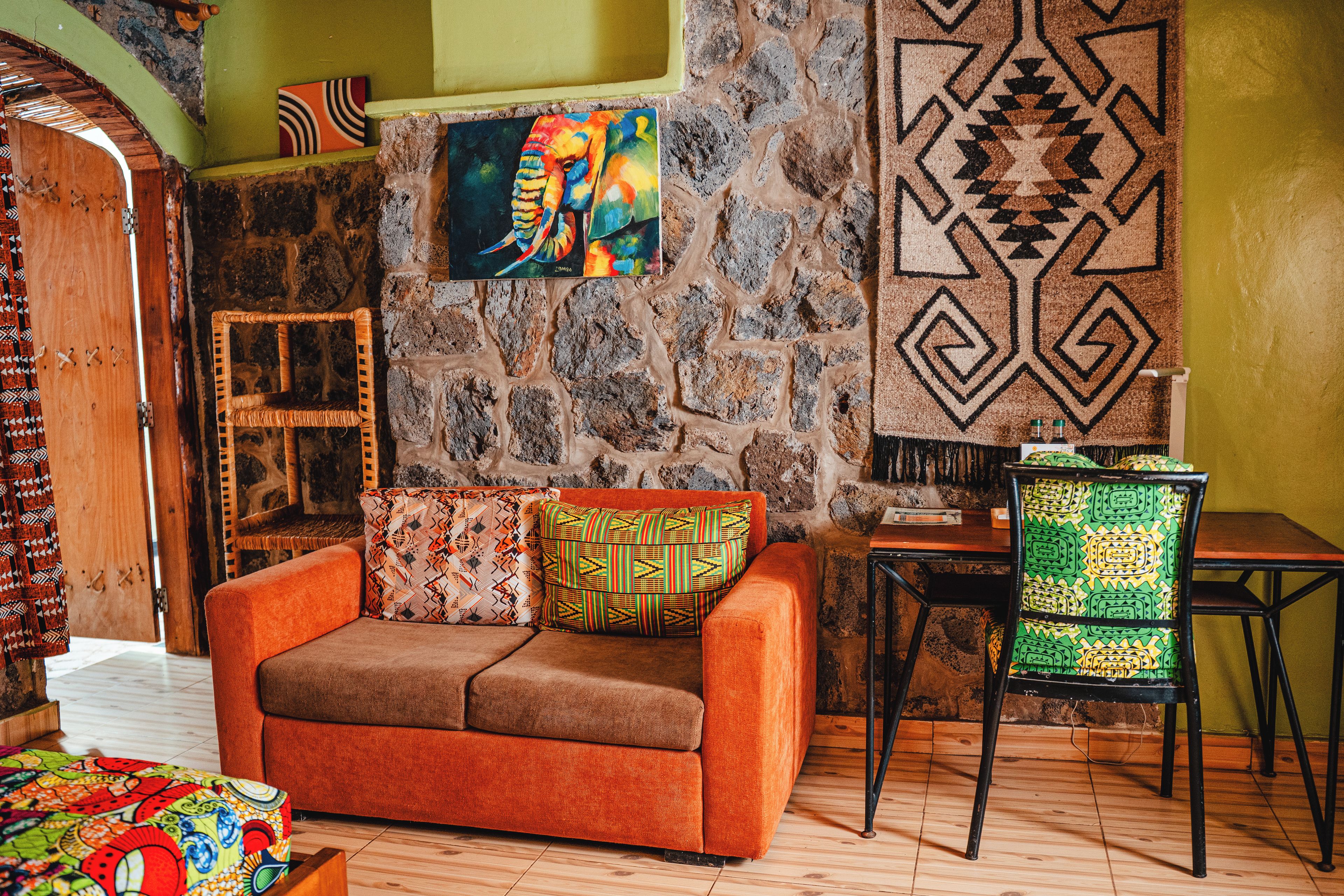 Una sala de estar acogedora con una pared de piedra, un cuadro llamativo y un tapete estampado.