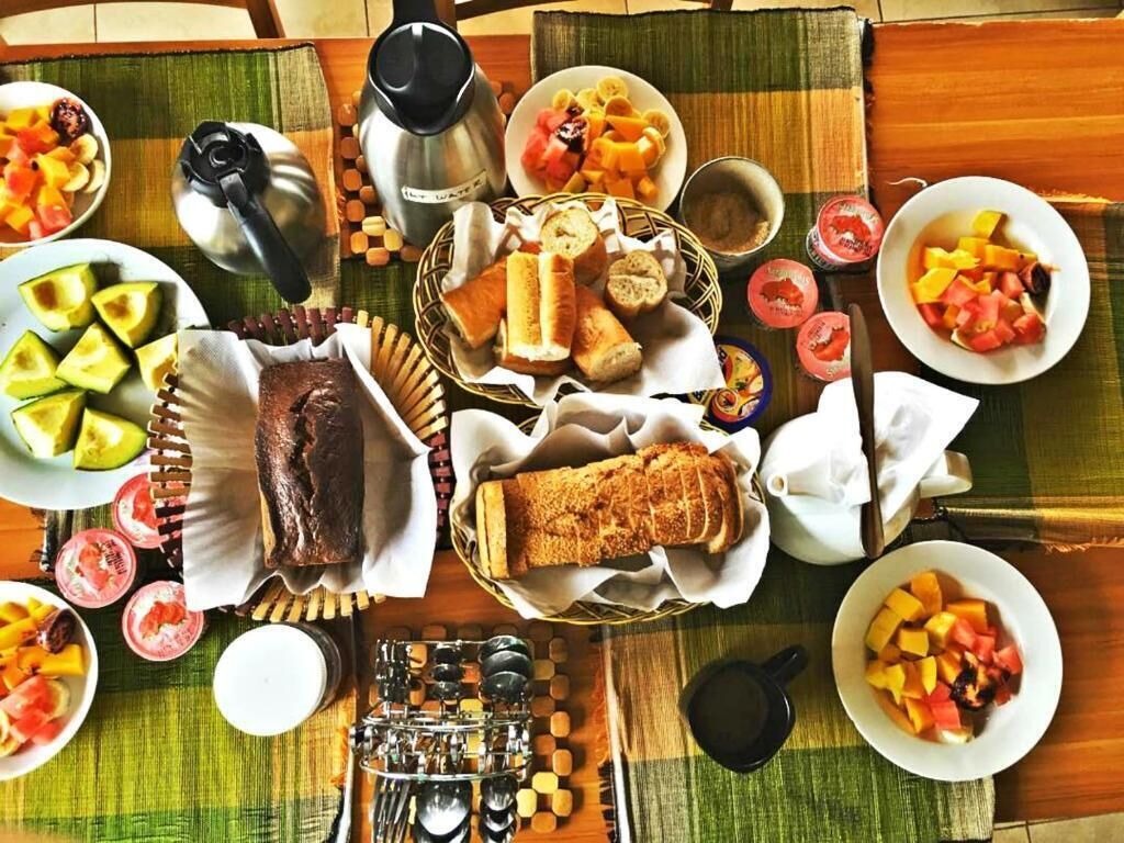 Ein Tisch mit verschiedenen Speisen und Besteck, darunter Brot, Obst und eine Kaffeemaschine.