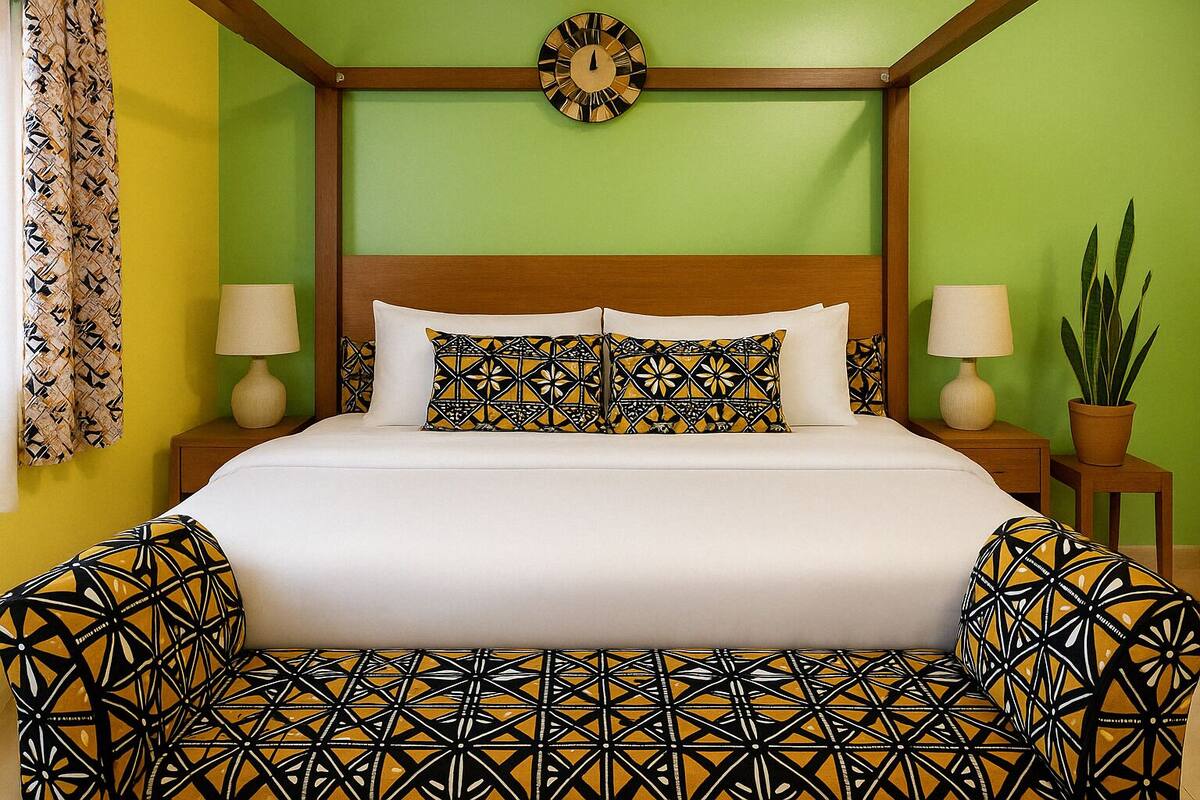 A bed with patterned pillows and a clock on the wall.