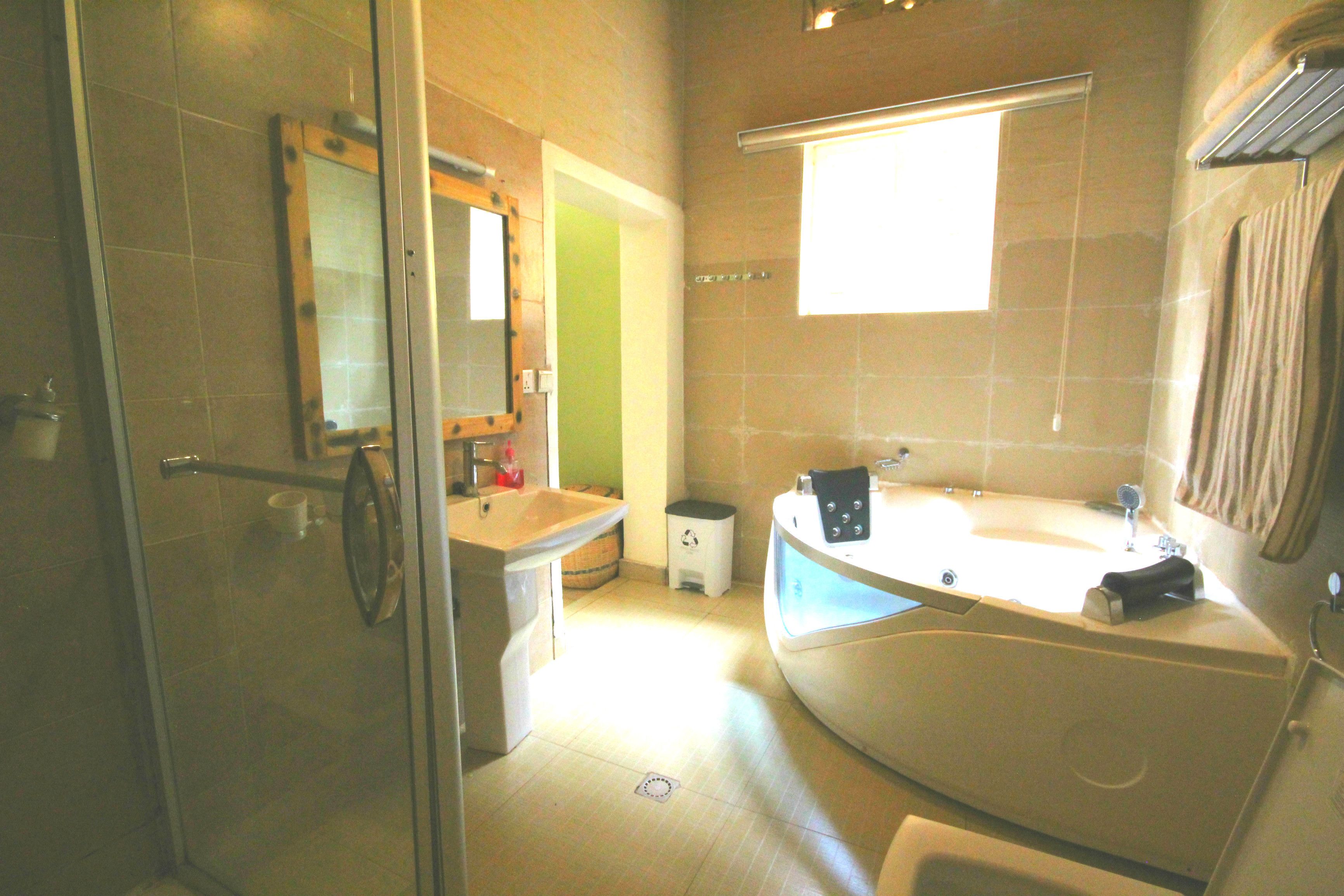 A modern bathroom with a glass shower enclosure, a large bathtub, and a separate sink area.