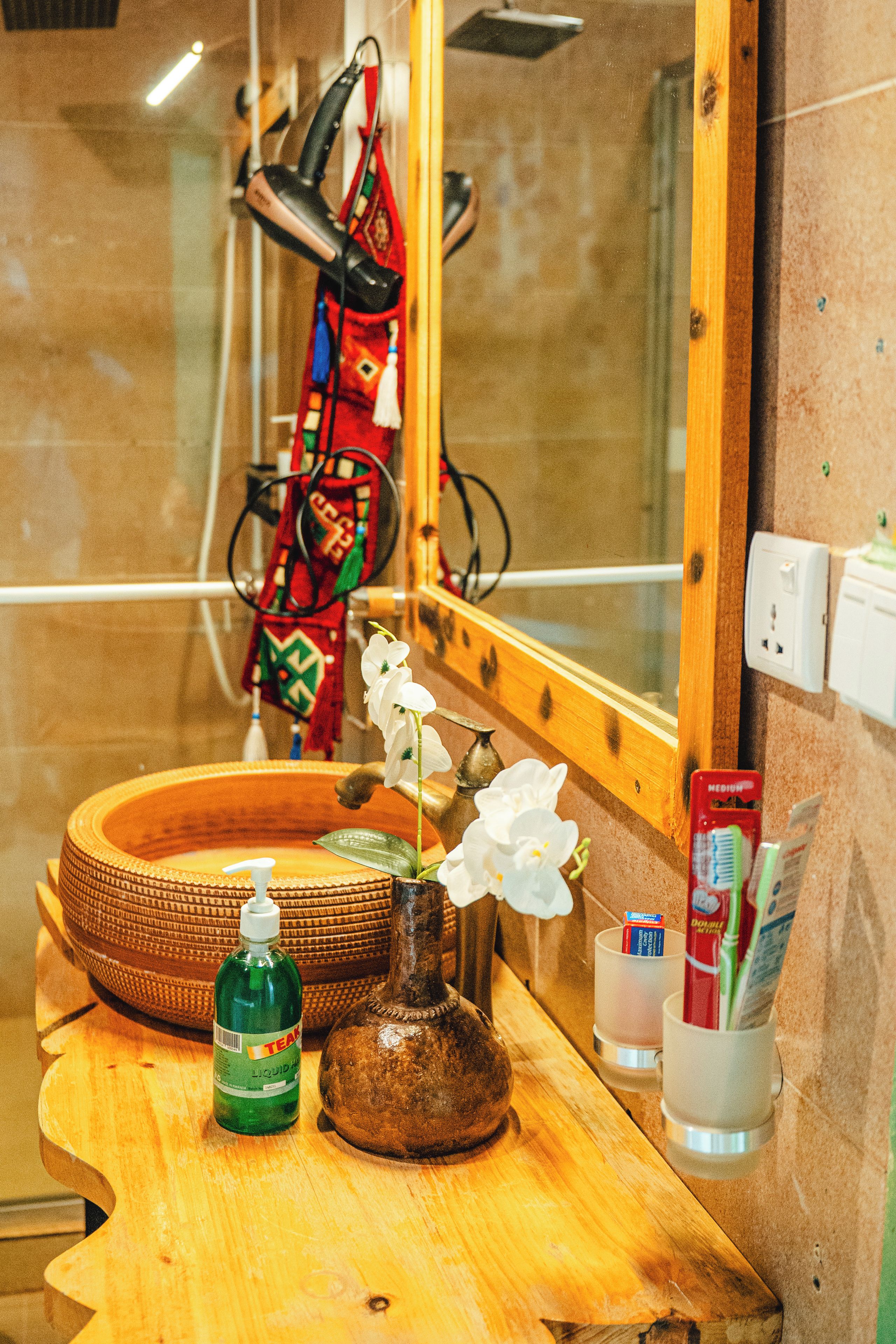 Ein Badezimmer mit einem Holzkosmetikschrank, einem Spiegel, einem Waschbecken und einer Seifenspenderflasche.