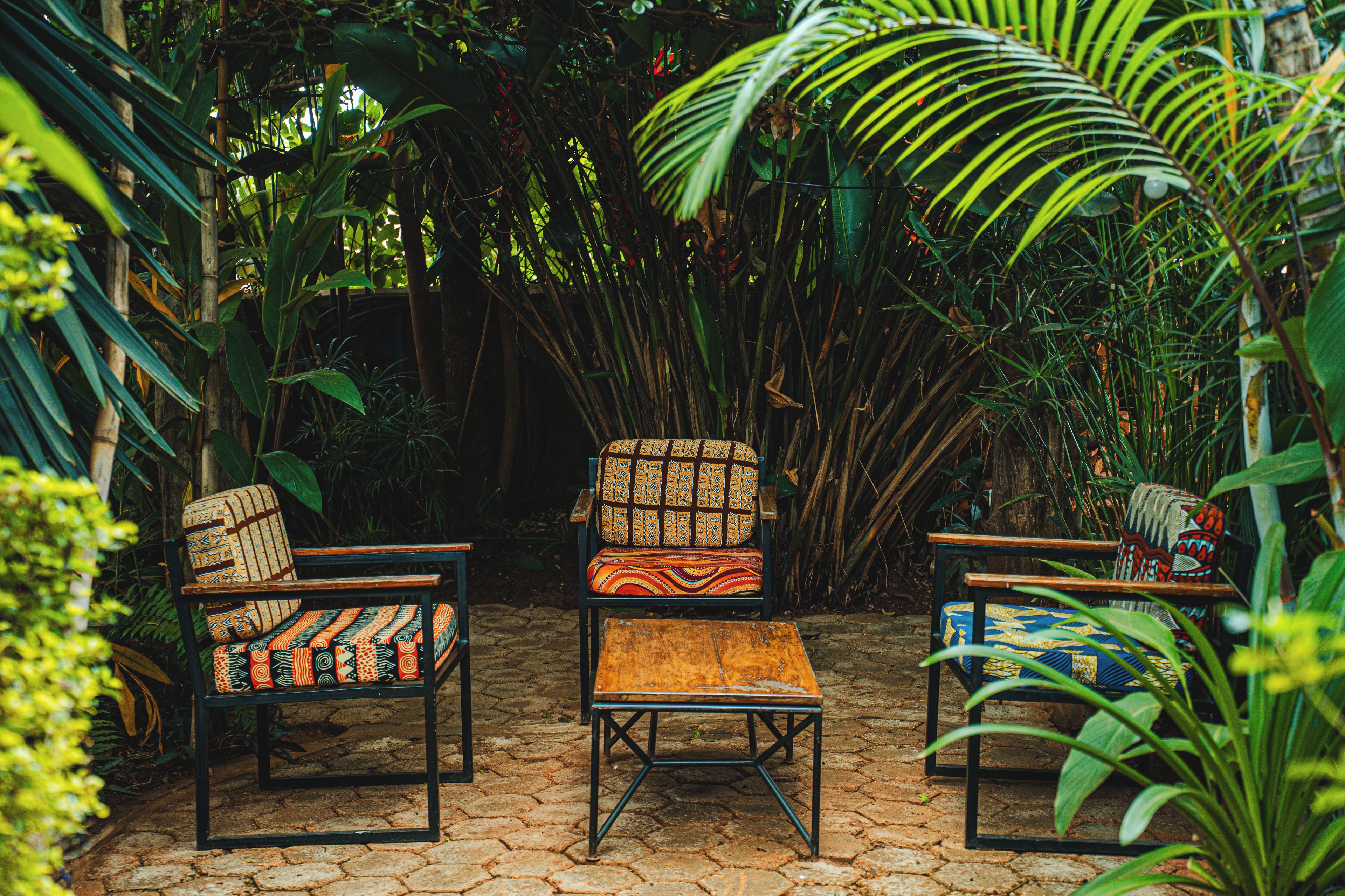 Un jardín con tres sillas y una mesa pequeña.