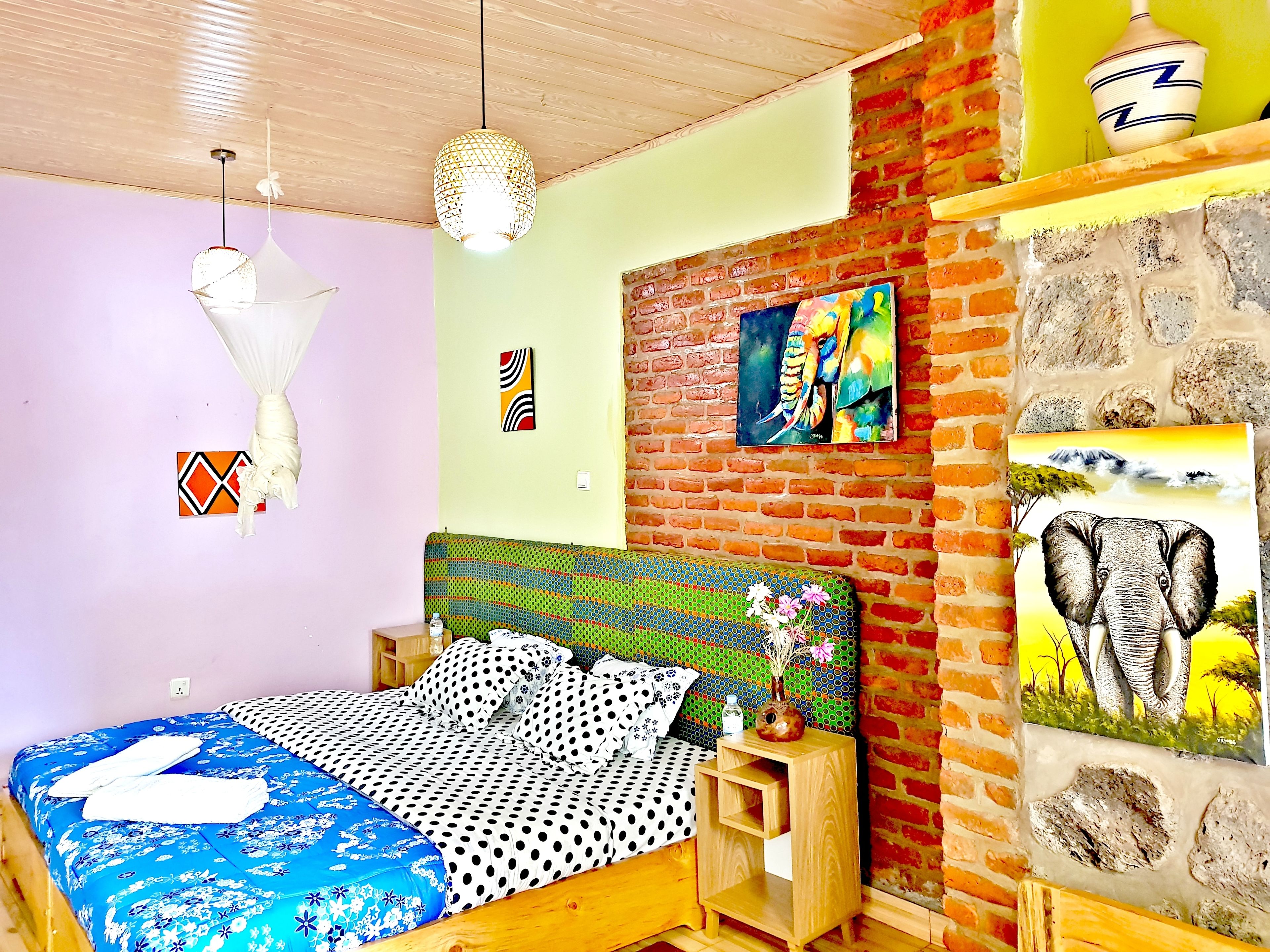 Un dormitorio con una cama, una mesita de noche de madera, una pared de ladrillo y un cuadro de un pájaro.