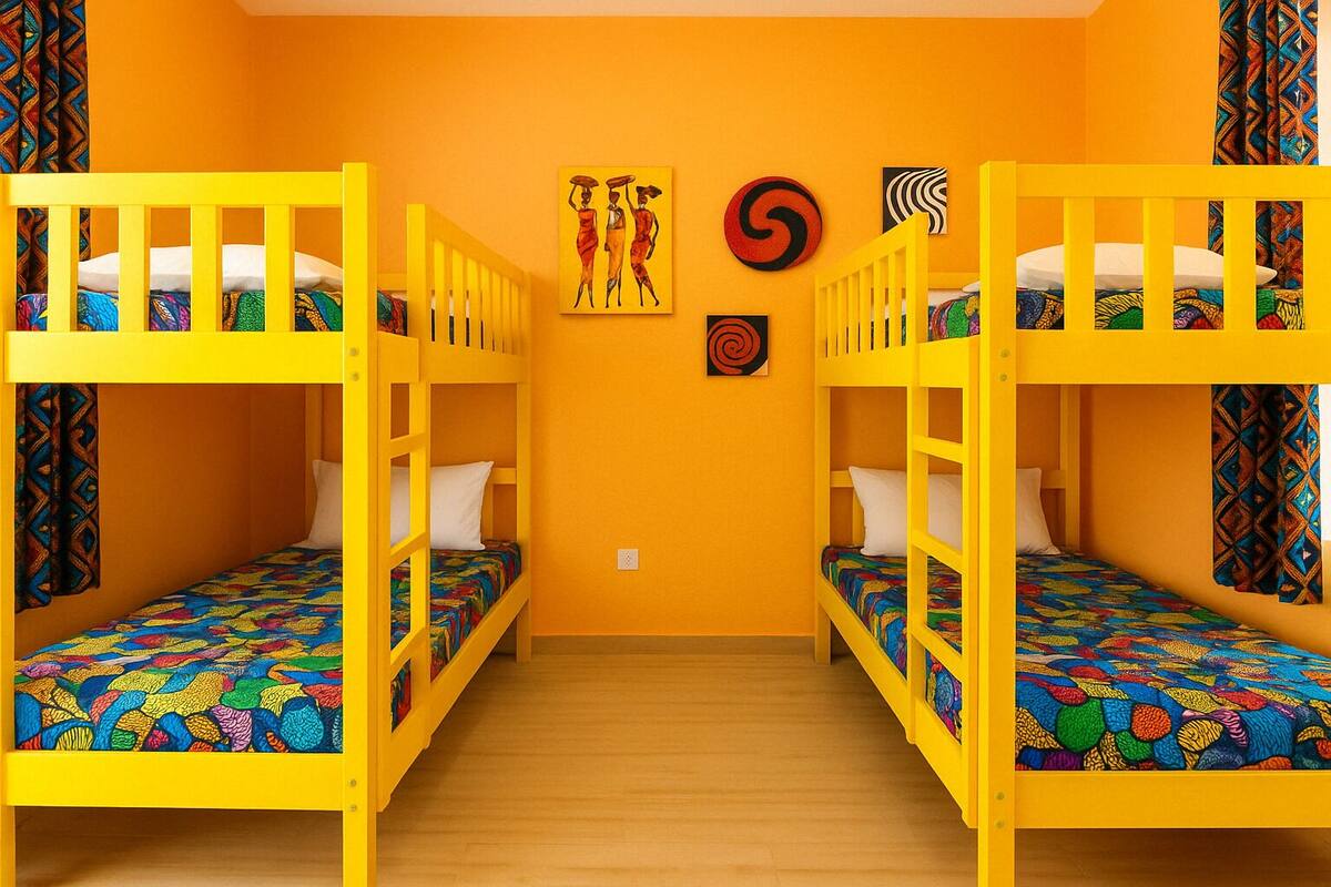 A room with two bunk beds, wooden flooring, and colorful patterned bedding.