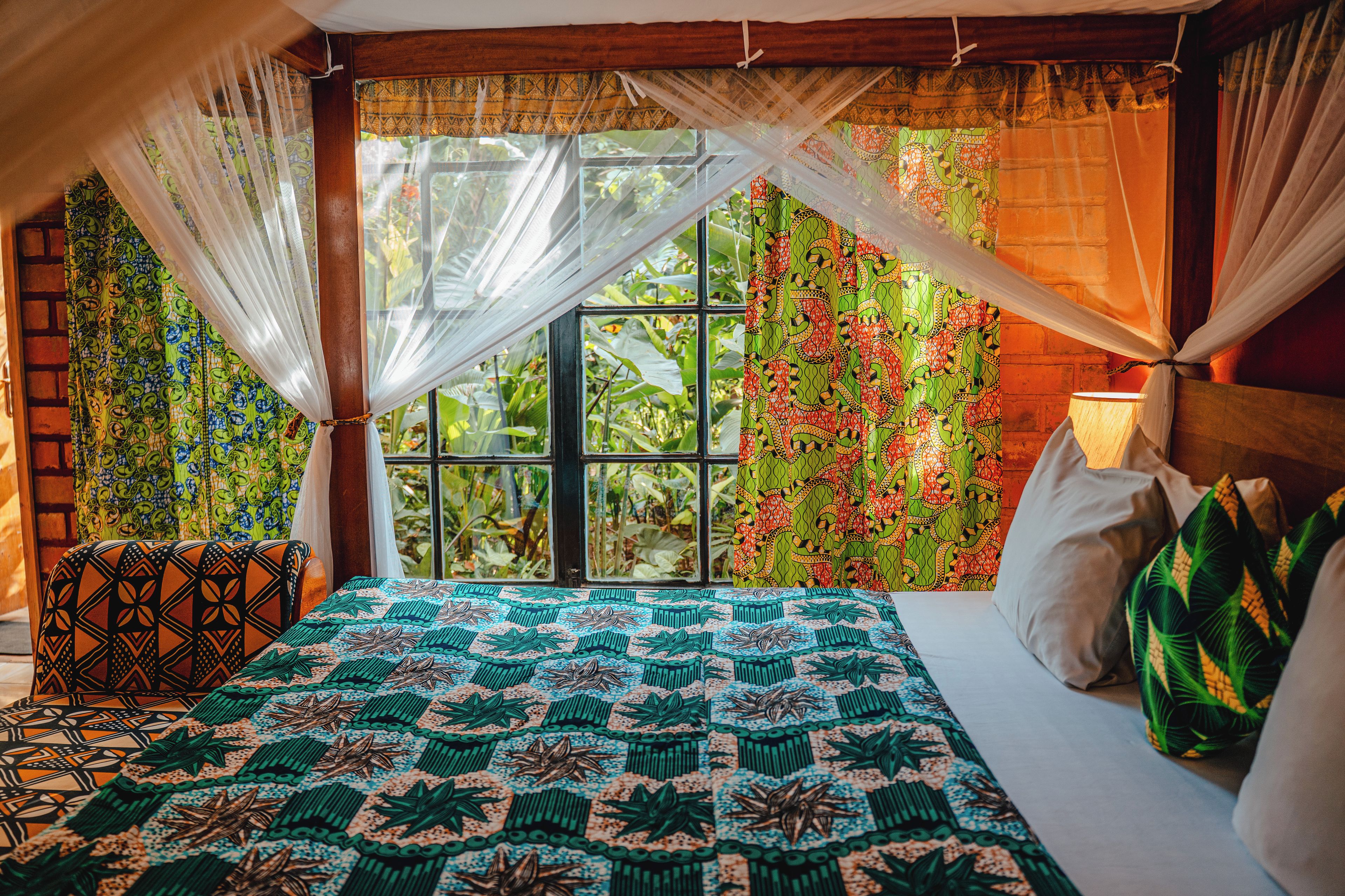 Ein Zimmer mit einem Bett, einem Vorhangfenster und Blick auf Grünfläche.
