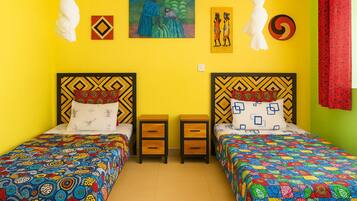 Una habitación con dos camas, cada una con una colcha estampada, un cuadro en la pared y una mesita de noche entre las camas.