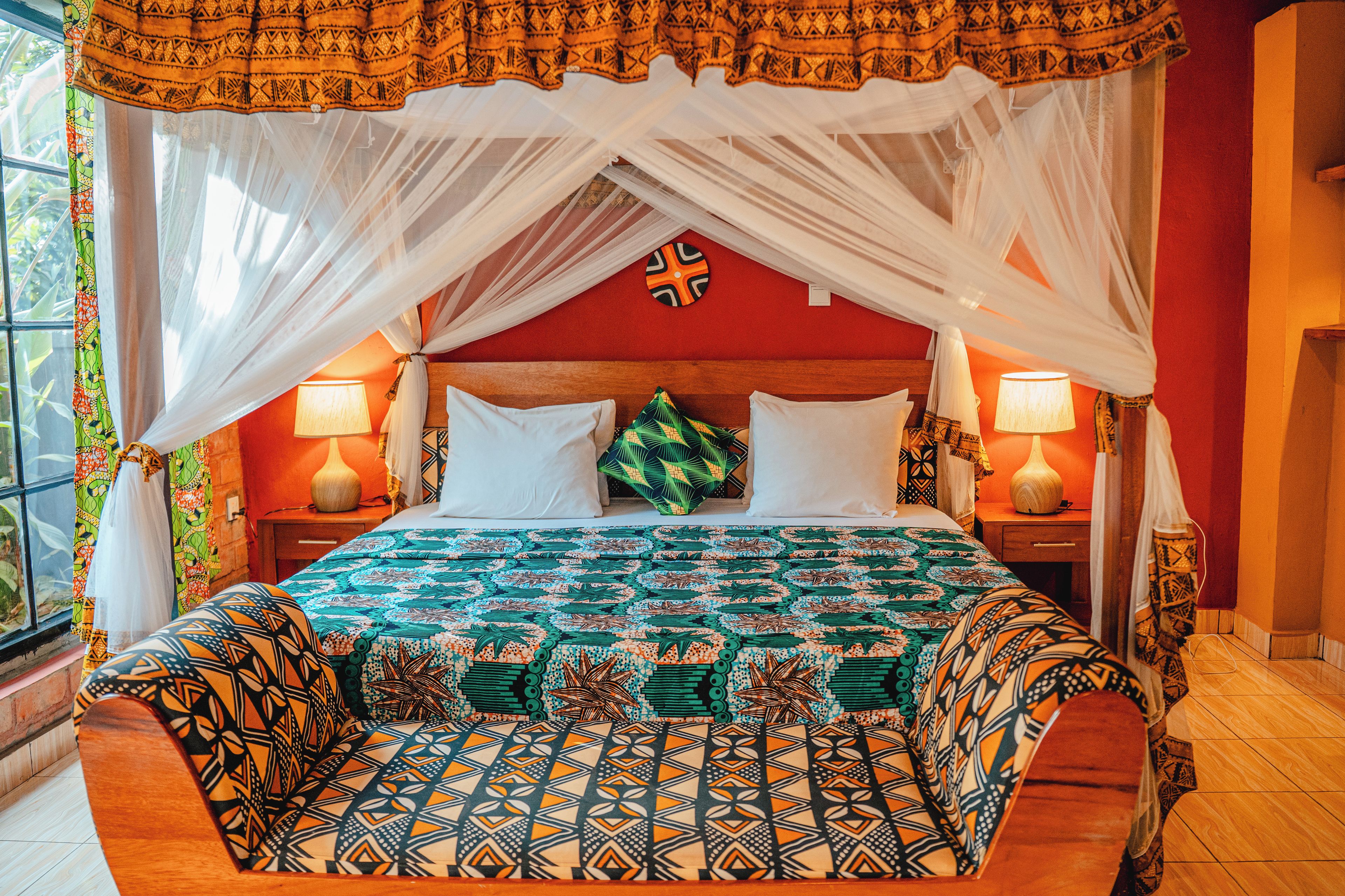 A room with a bed, a nightstand, a lamp, and a window with curtains.