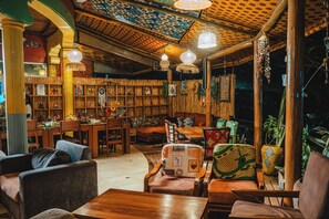 An interior with wooden furniture, a dining area, and a wall with various decorative items. - Yambi Guesthouse (Kigali)