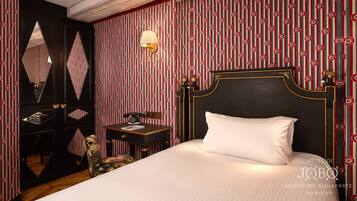 Una habitación de hotel con una cama grande, un escritorio con teléfono y un espejo en la pared.