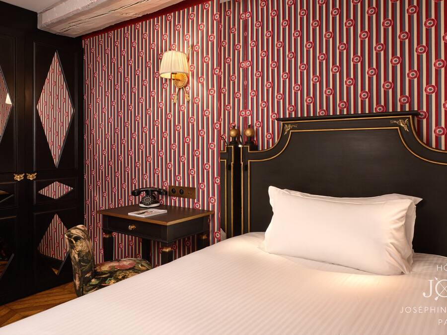 Una habitación de hotel con una cama grande, un escritorio con teléfono y un espejo en la pared.