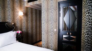 Een slaapkamer met een bed, een nachtkastje met een bloevas en een garderobe met een spiegel.