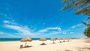 En privat strand, hvidt sand, liggestole, parasoller