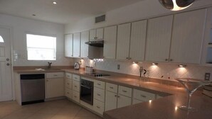 A modern kitchen with white cabinets, a built-in oven, and a large island with a glass top. - Villa 244D at Jolly Harbour (Jolly Harbour)