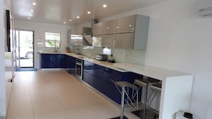 A modern kitchen with a central island, stainless steel appliances, and a view of the outside. - Villa 227E at Jolly Harbour-Adults Only (Jolly Harbour)