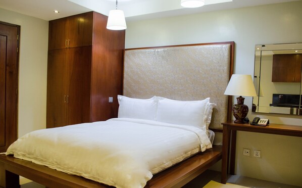 A neatly made bed with white linens in a hotel room. - Ritz Hotel (Angeles City)