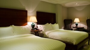 A hotel room with two beds, each with a nightstand and a lamp. - Ritz Hotel (Angeles City)