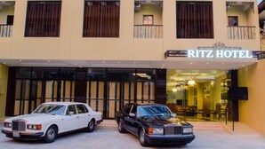 A hotel entrance with two luxury cars parked in front. - Ritz Hotel (Angeles City)