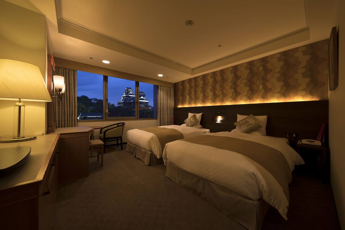 A hotel room with two beds, a desk, and a chair.