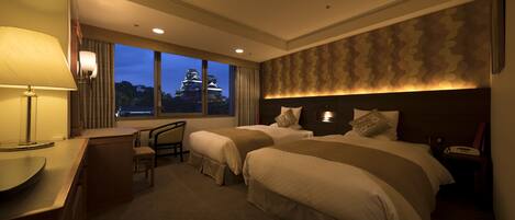 Quarto de hotel com duas camas, uma escrivaninha e uma cadeira.