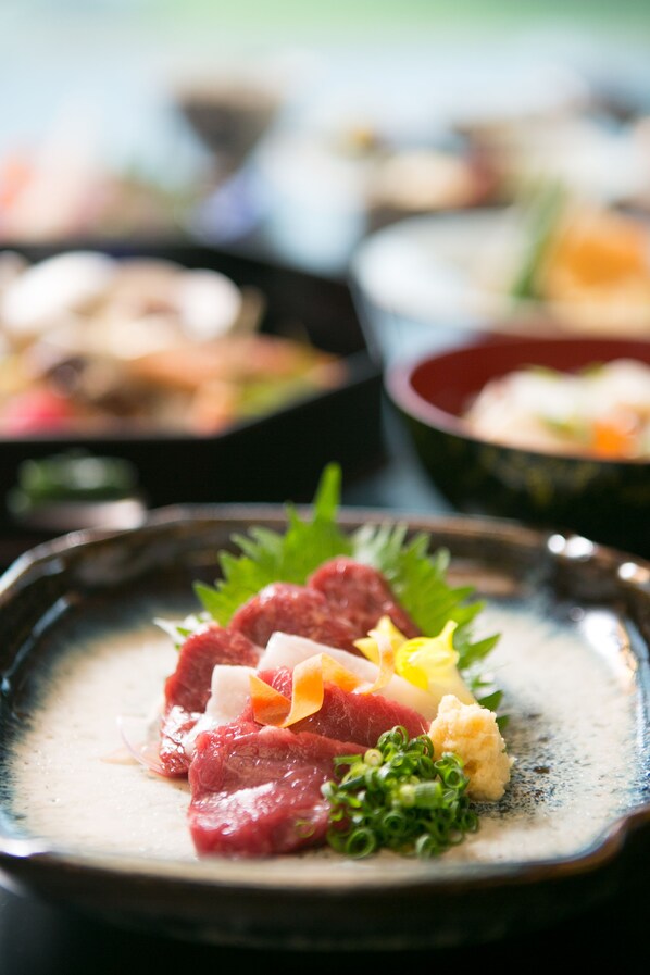 A close-up of a dish with various ingredients, including meat and vegetables, on a ceramic plate. - KKR Hotel Kumamoto (Kumamoto)