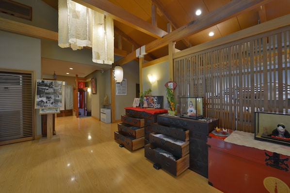 A traditional Japanese interior with wooden floors, a red counter, and a display of cultural items.