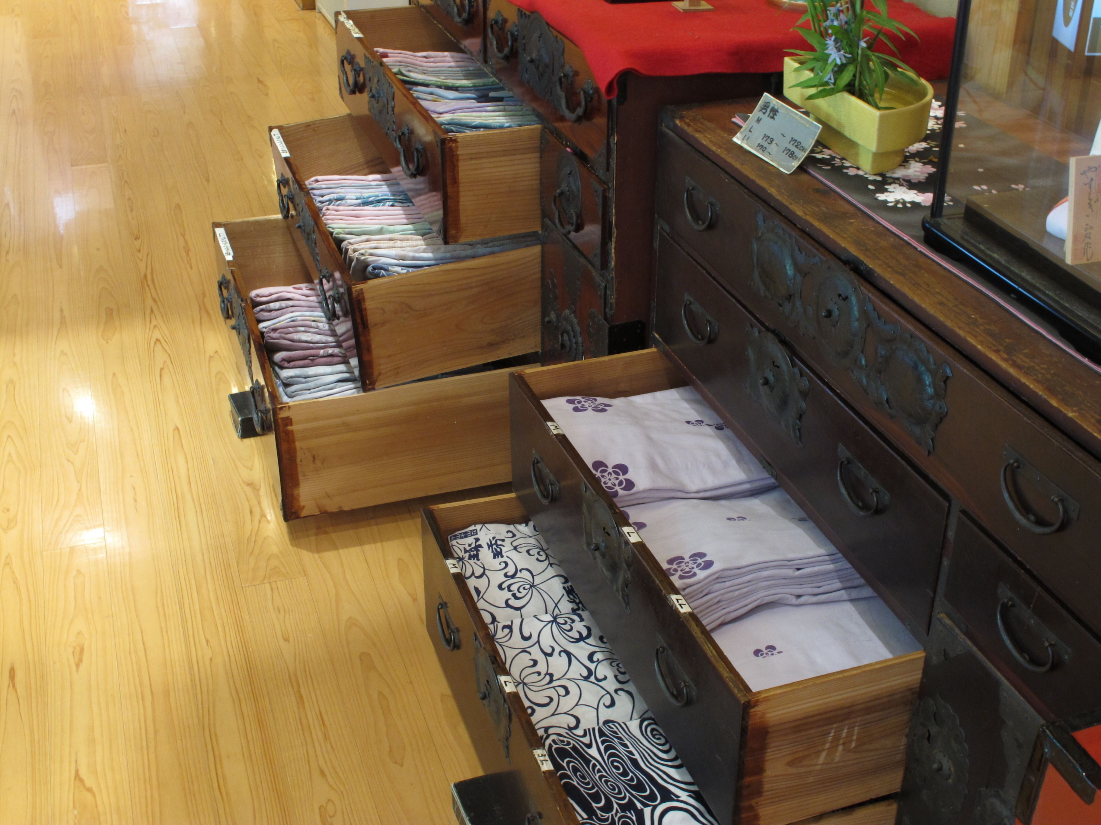 A hotel room with wooden furniture, including a dresser and a bed with a floral bedspread.