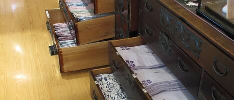 A hotel room with wooden furniture, including a dresser and a bed with a floral bedspread.