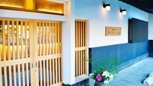 Una entrada japonesa tradicional con puertas correderas de madera, un farol de piedra y un letrero en la pared.