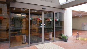 Der Eingang des Star Hotel Yokohama mit Glastüren, Topfpflanzen und einem gefliesten Boden.