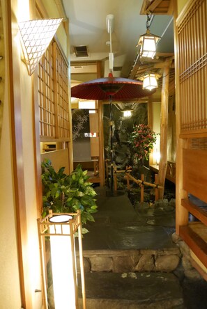 Ein traditioneller japanischer Gang mit Holzbauten, einem Steinweg und einem hängenden Laternenleuchter.
