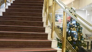 Eine prachtvolle Treppe mit hölzernen Stufen und goldenen Geländern, die zu einer oberen Etage führt.
