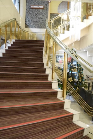 A grand staircase with wooden steps and golden railings, leading to an upper floor.