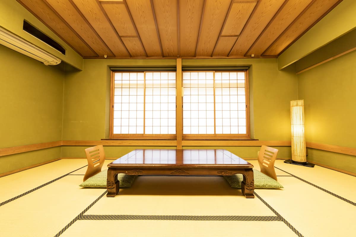 Um quarto japonês tradicional com tatames, uma mesa de madeira baixa e portas deslizantes.