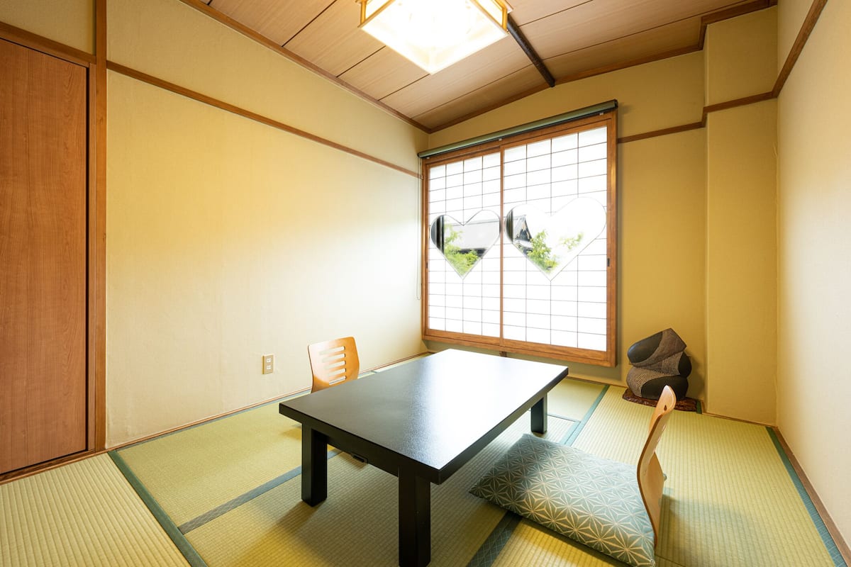 Um quarto japonês tradicional com tatames, uma mesa baixa e portas deslizantes shoji.
