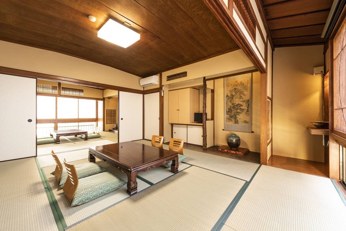 Um quarto japonês tradicional com tatames, uma mesa de madeira baixa e portas deslizantes.