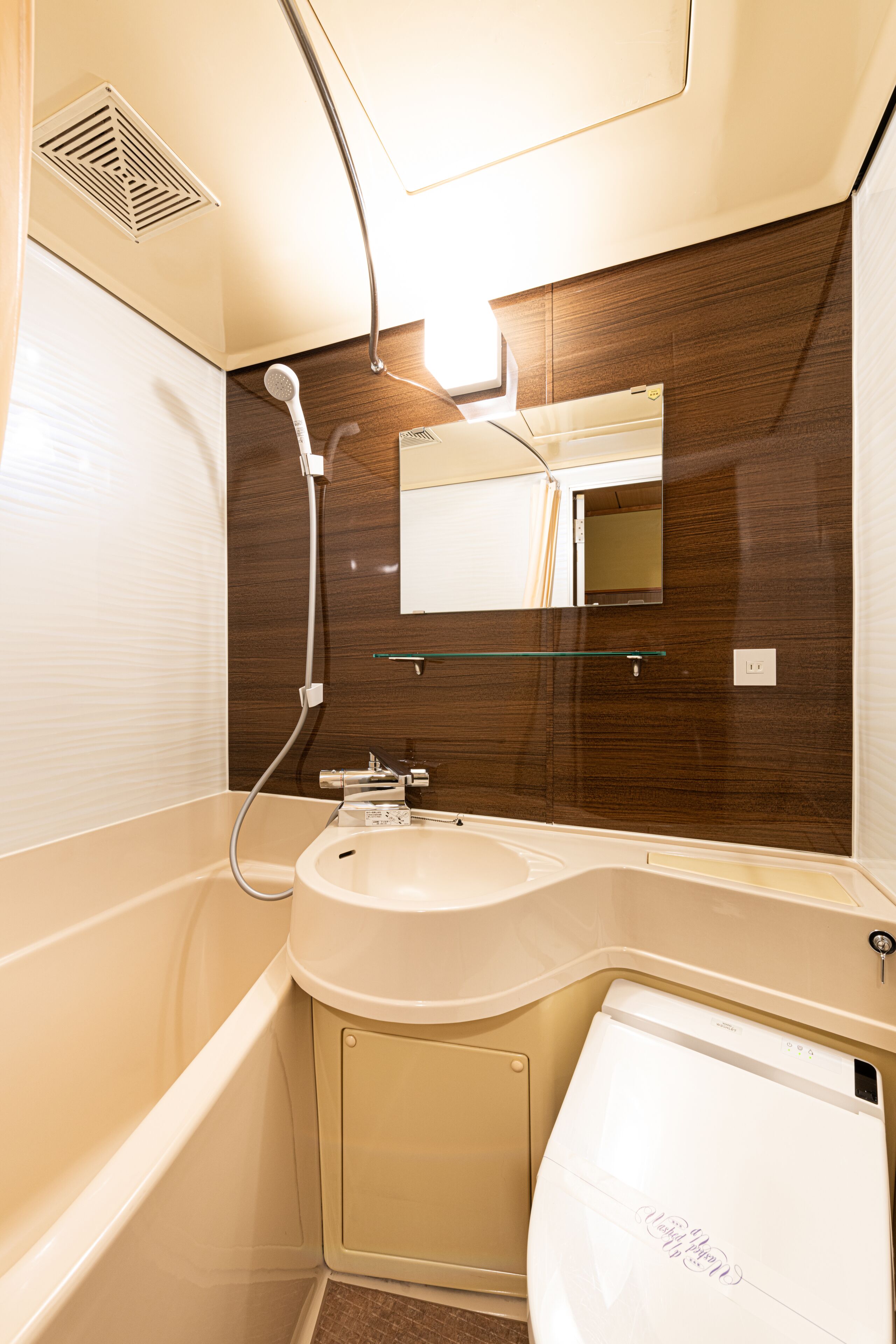 A compact bathroom with a white sink, mirror, and toilet.
